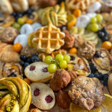 AM Board featuring assorted seasonal baked goods, fruit, and pastries close-up view