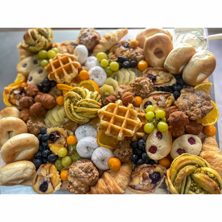 AM Board with assorted baked goods, fruit, bagels, muffins, tarts, and pastries arranged on a platter