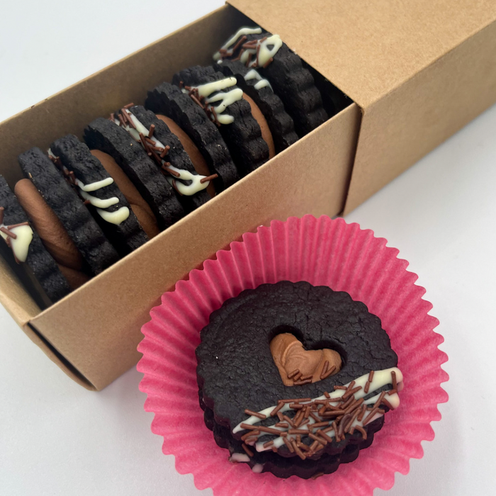 Quadruple Chocolate Sandwich cookies with black cocoa wafers, milk chocolate ganache, white and dark chocolate decoration in a brown box and pink wrapper